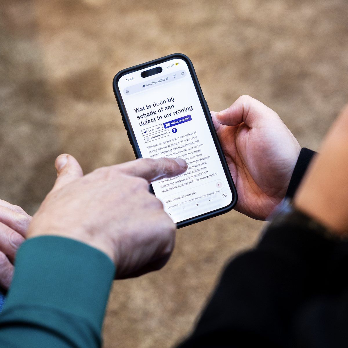 Twee mensen lezen samen een brief van een woningcorporatie op een telefoon met de Tolkie-leeshulp